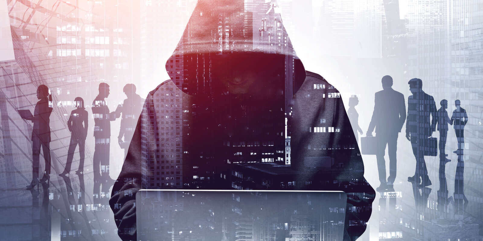 young hacker in hoodie using laptop in blurry city